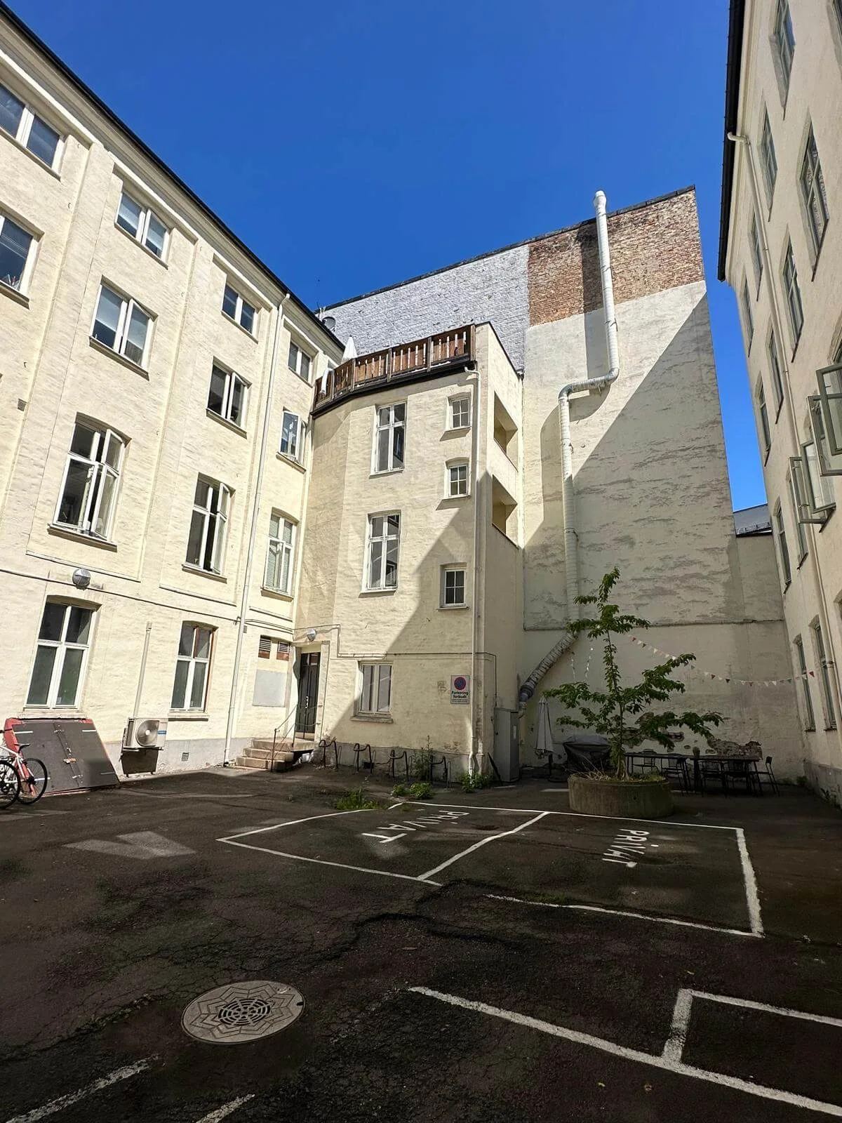 Asfaltert bakgård med parkeringsoppmerking og tilstøtende bygninger