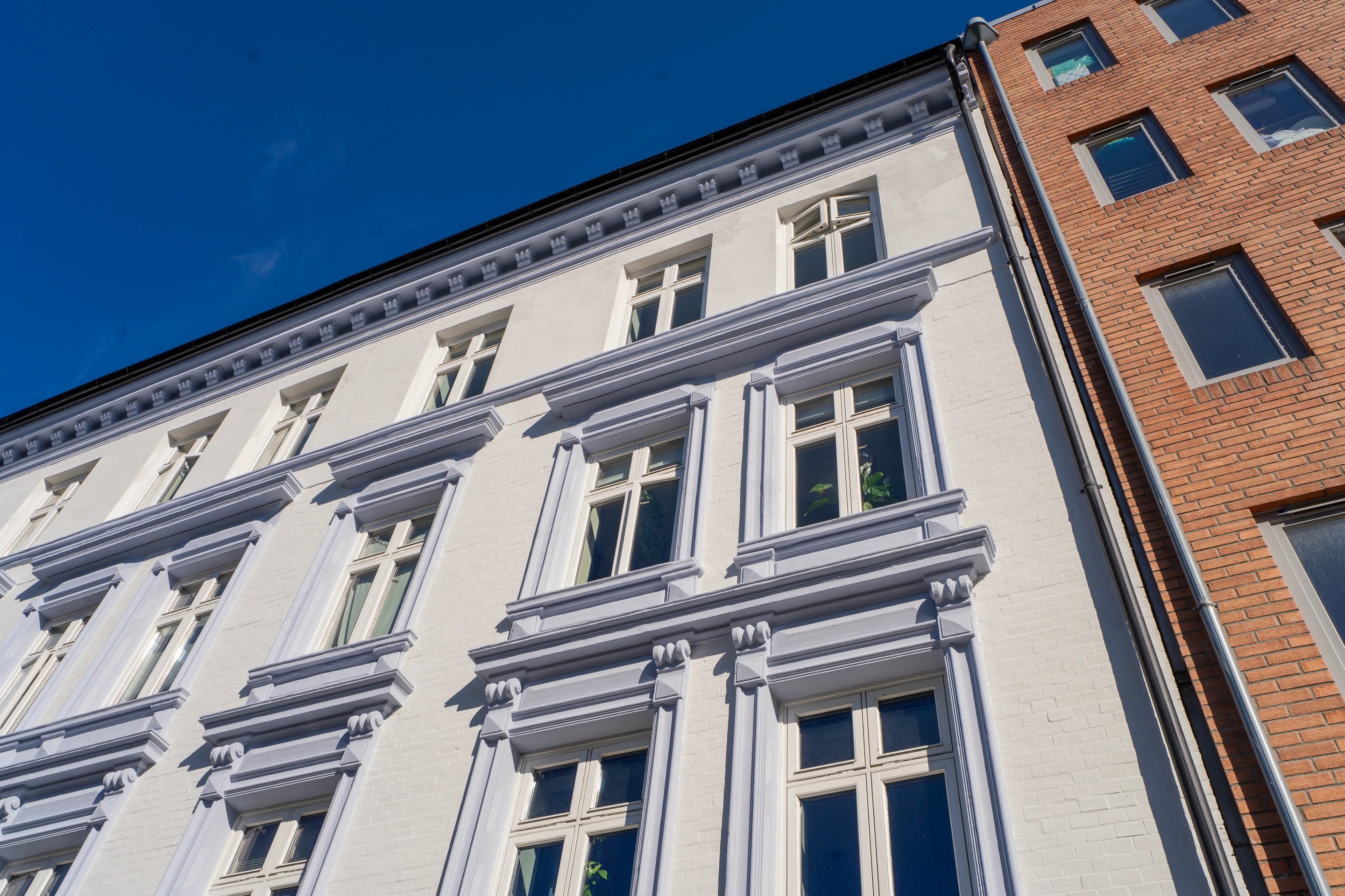 Pusset bygårdsfasade med vindusomramming og gesims