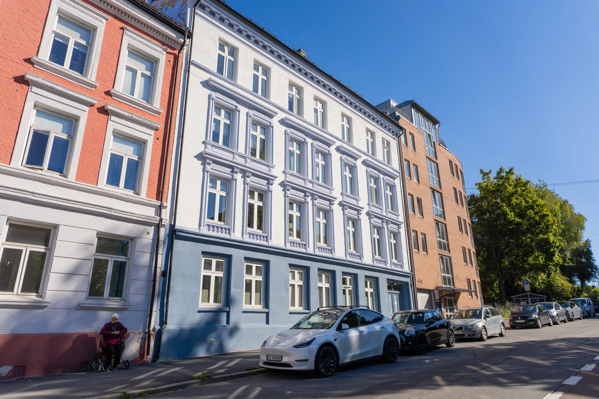 Grå bygårdsfasade med hvite gesimser og vindusdetaljer